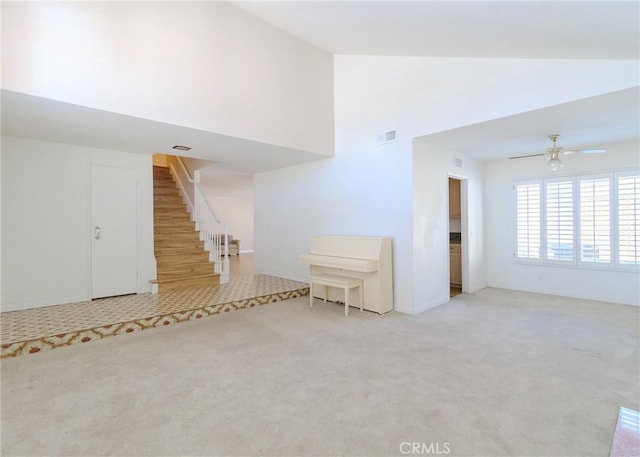 unfurnished living room with light carpet, visible vents, stairway, and a ceiling fan