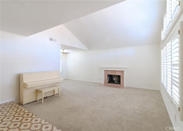 unfurnished room with visible vents, a fireplace with flush hearth, carpet flooring, ceiling fan, and high vaulted ceiling