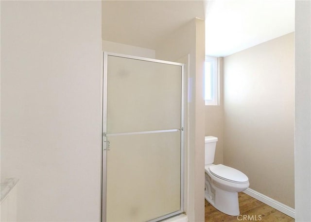 full bathroom with a stall shower, wood finished floors, toilet, and baseboards