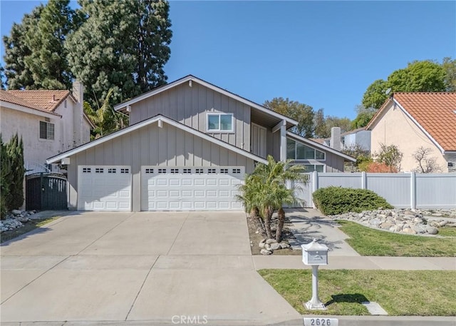 view of front of property featuring concrete driveway, board and batten siding, fence, and a gate