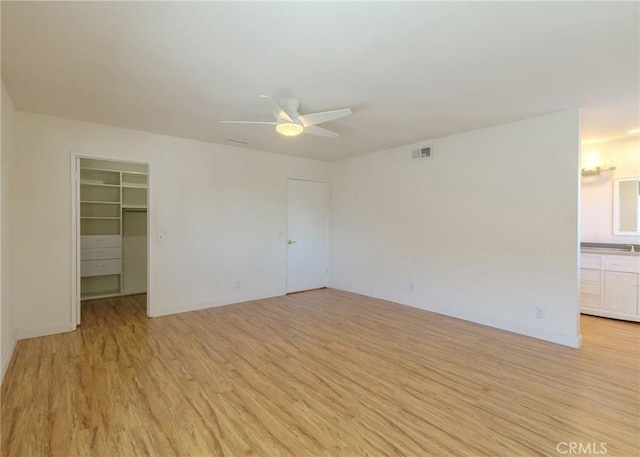 unfurnished room with a ceiling fan, visible vents, light wood-style flooring, and baseboards