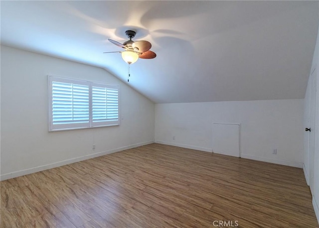 additional living space with baseboards, a ceiling fan, vaulted ceiling, and wood finished floors