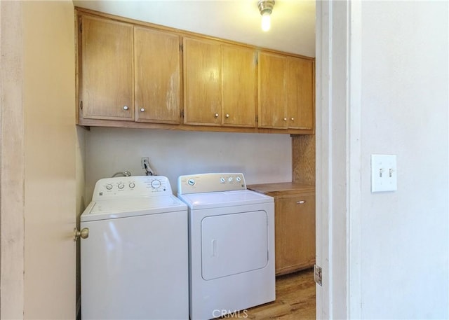 laundry room with cabinet space, light wood finished floors, and washing machine and clothes dryer