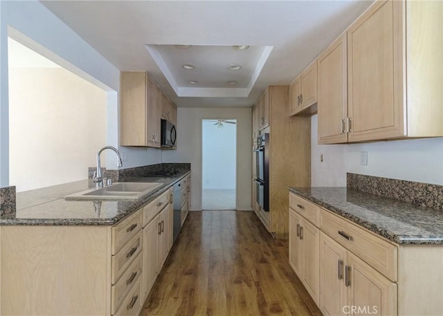 kitchen with a raised ceiling, dishwasher, light brown cabinets, black microwave, and a sink