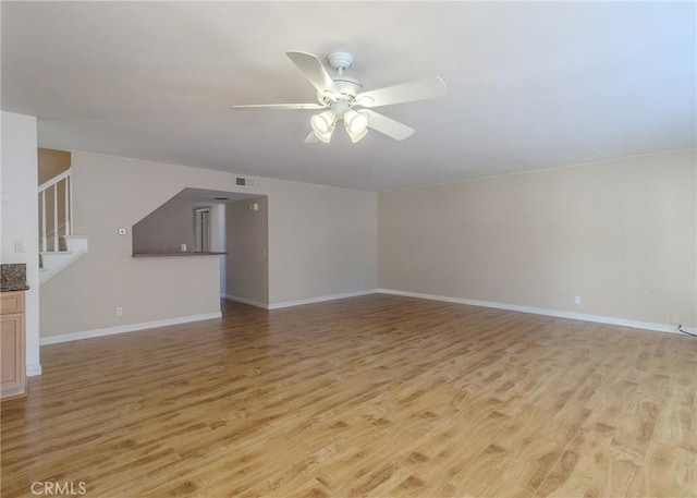 unfurnished living room featuring visible vents, baseboards, ceiling fan, stairs, and light wood-type flooring