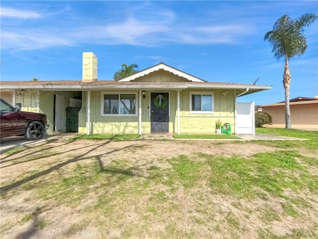 ranch-style house with a chimney, a front lawn, and board and batten siding