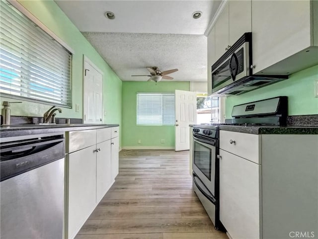 kitchen featuring stainless steel appliances, dark countertops, white cabinetry, and a textured ceiling