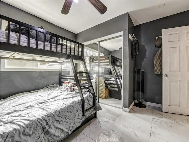 bedroom featuring marble finish floor, a closet, a ceiling fan, and baseboards