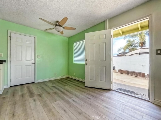 interior space with light wood-style flooring, a textured ceiling, baseboards, and a ceiling fan