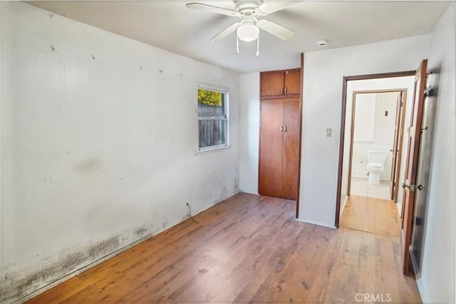 unfurnished bedroom with ceiling fan, a closet, and light wood-style floors