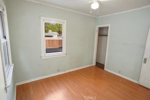 unfurnished bedroom featuring baseboards, a closet, ornamental molding, and wood finished floors