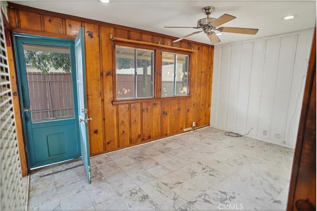 interior space featuring wooden walls and a ceiling fan