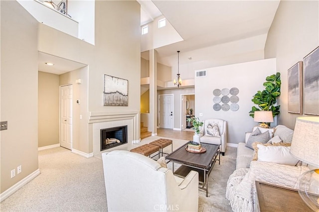 living room featuring baseboards, visible vents, light colored carpet, a high ceiling, and a fireplace