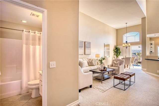 carpeted living area with a chandelier, tile patterned flooring, visible vents, and baseboards