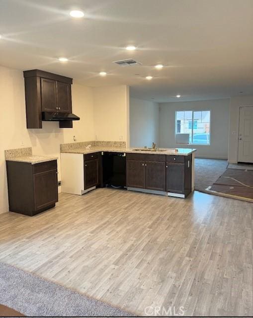 kitchen with light wood finished floors, black dishwasher, open floor plan, light countertops, and a sink