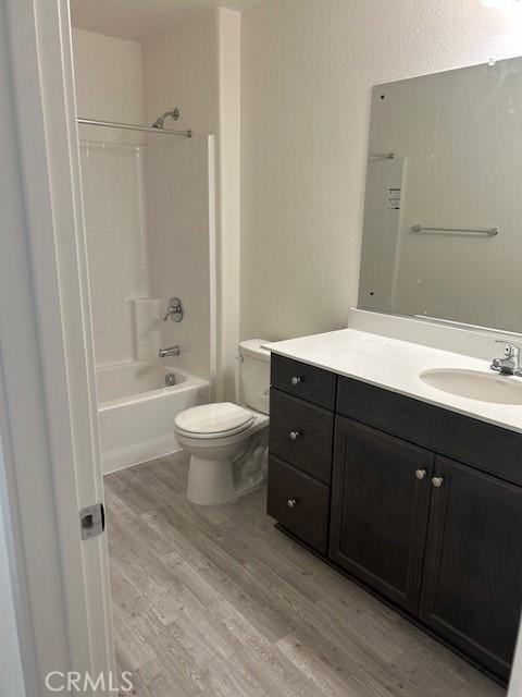 full bathroom featuring toilet, shower / bathtub combination, wood finished floors, and vanity