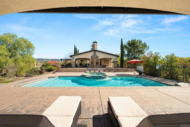 view of pool featuring a pool with connected hot tub, a patio area, fence, and a mountain view