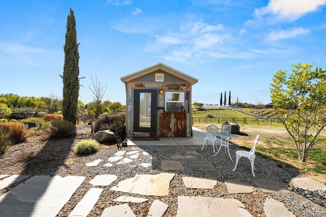 view of outbuilding with a rural view, fence, and an outdoor structure