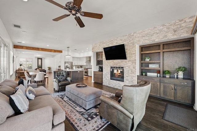 living room with ceiling fan, a stone fireplace, recessed lighting, dark wood-style flooring, and visible vents