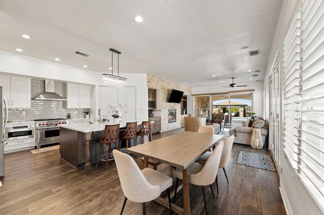 dining area with a fireplace, visible vents, dark wood-style flooring, and recessed lighting