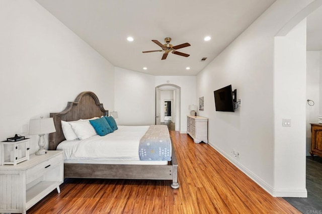 bedroom featuring baseboards, visible vents, arched walkways, wood finished floors, and recessed lighting