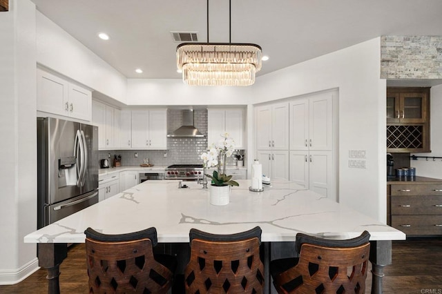 kitchen featuring appliances with stainless steel finishes, a large island, white cabinetry, and wall chimney range hood