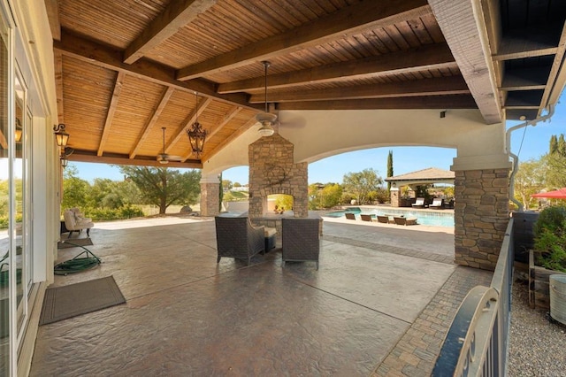 view of patio featuring a gazebo, exterior kitchen, an outdoor stone fireplace, and an outdoor pool