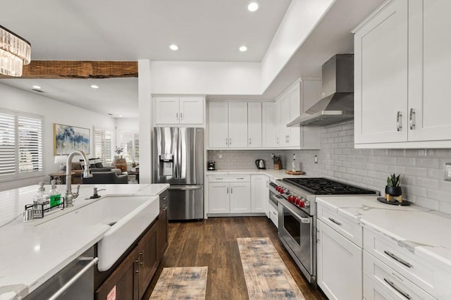 kitchen with dark wood finished floors, backsplash, appliances with stainless steel finishes, white cabinetry, and wall chimney exhaust hood