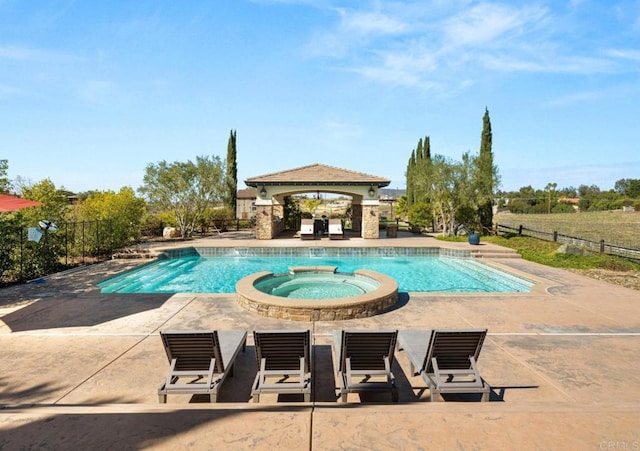 view of pool featuring a pool with connected hot tub, fence, a patio, and a gazebo