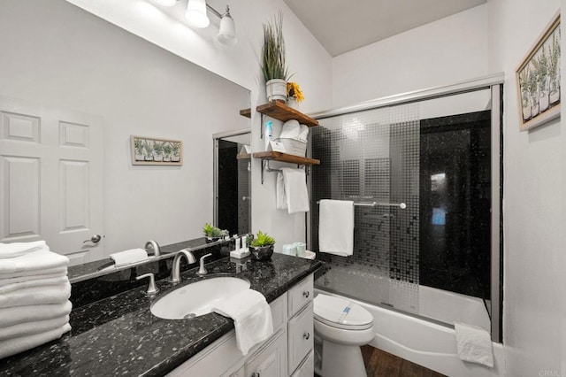 bathroom with combined bath / shower with glass door, vanity, toilet, and wood finished floors