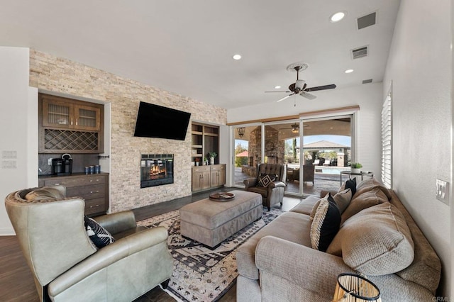 living area featuring dark wood-style floors, a stone fireplace, visible vents, and recessed lighting