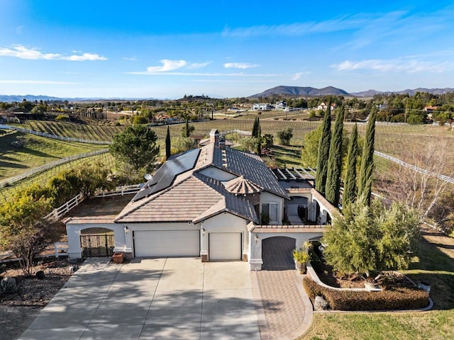 view of front facade featuring stucco siding, concrete driveway, an attached garage, roof mounted solar panels, and a mountain view