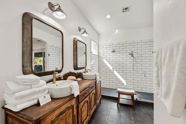 bathroom featuring double vanity, walk in shower, a sink, and visible vents