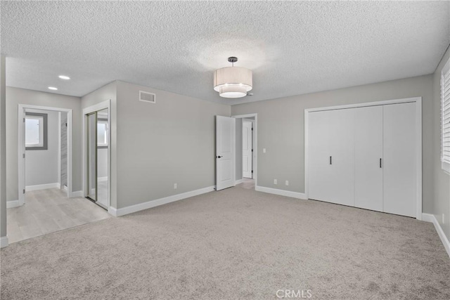 interior space featuring light carpet, a textured ceiling, visible vents, and baseboards