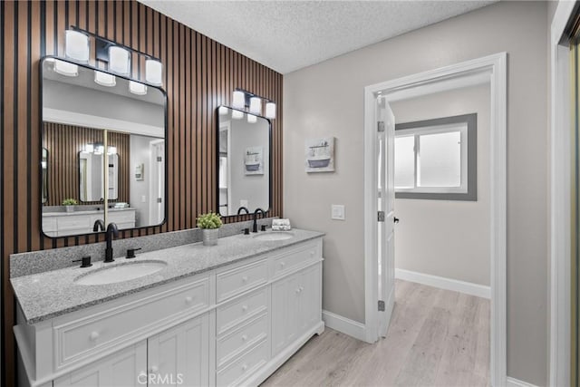 bathroom featuring double vanity, a sink, a textured ceiling, and wood finished floors