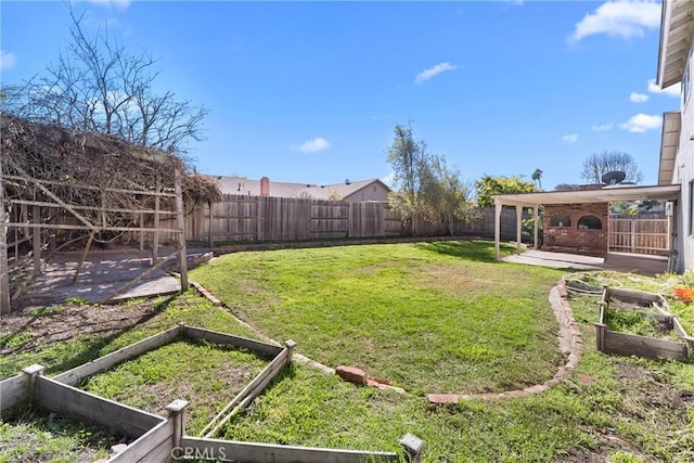 view of yard with a patio area, a fenced backyard, and a vegetable garden