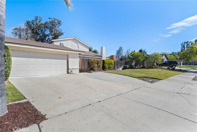 view of front facade featuring a garage, fence, concrete driveway, stucco siding, and a front yard