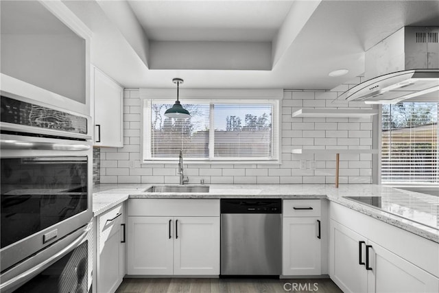 kitchen with island range hood, white cabinets, light stone countertops, stainless steel appliances, and a sink