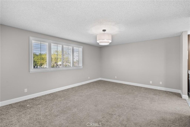 empty room featuring carpet, a textured ceiling, and baseboards