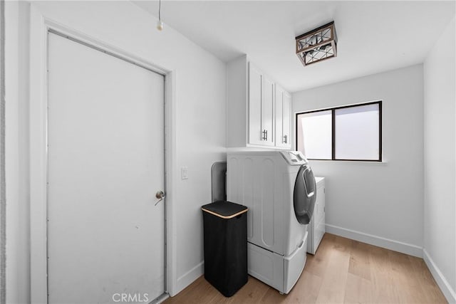 washroom featuring washing machine and dryer, baseboards, cabinet space, and light wood finished floors