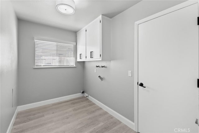 clothes washing area with cabinet space, light wood-style flooring, hookup for a washing machine, and baseboards