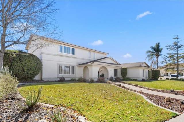 traditional home featuring a front yard and stucco siding