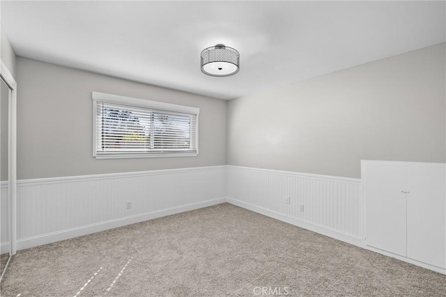 empty room with light carpet and wainscoting