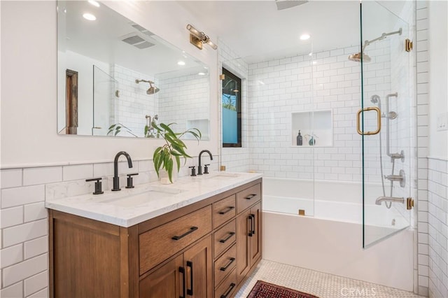 full bathroom with double vanity, visible vents, tile walls, and a sink