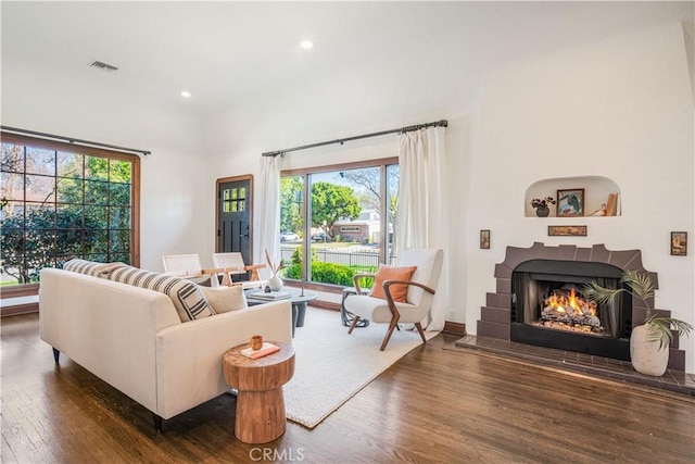 living room with a tile fireplace, recessed lighting, a towering ceiling, visible vents, and dark wood finished floors