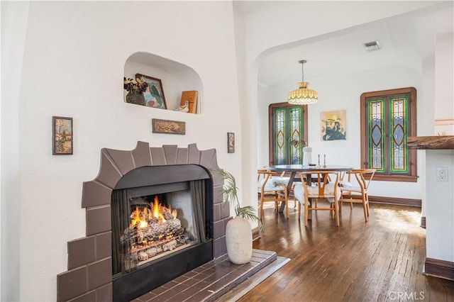 interior space with a lit fireplace, dark wood finished floors, visible vents, and baseboards