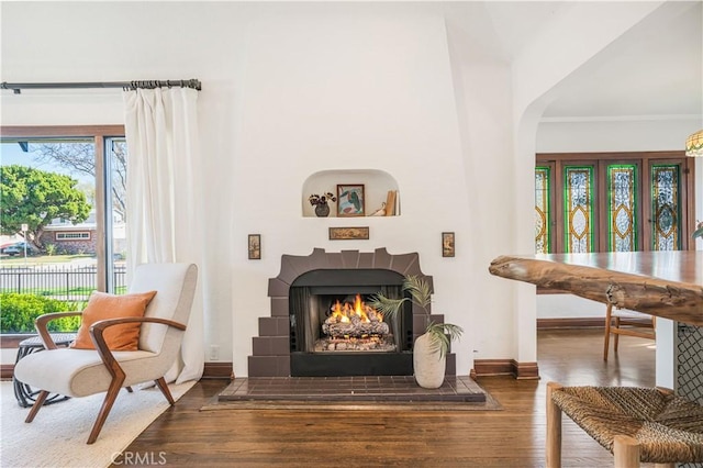 living area featuring dark wood-type flooring, a tile fireplace, and baseboards