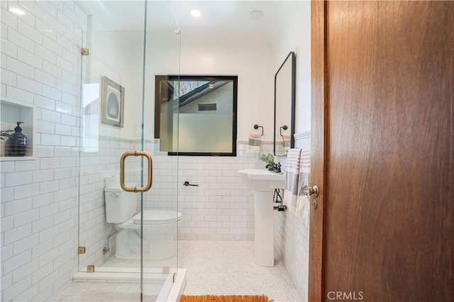 full bath featuring tile walls, a shower stall, and tile patterned floors