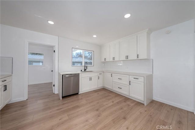 kitchen with light wood-style floors, light countertops, a sink, and stainless steel dishwasher