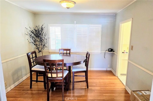 dining room featuring crown molding, baseboards, and wood finished floors